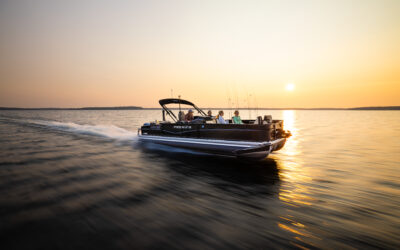 Premier Sunsation Angler pontoon boat cruising across a lake at sunset.