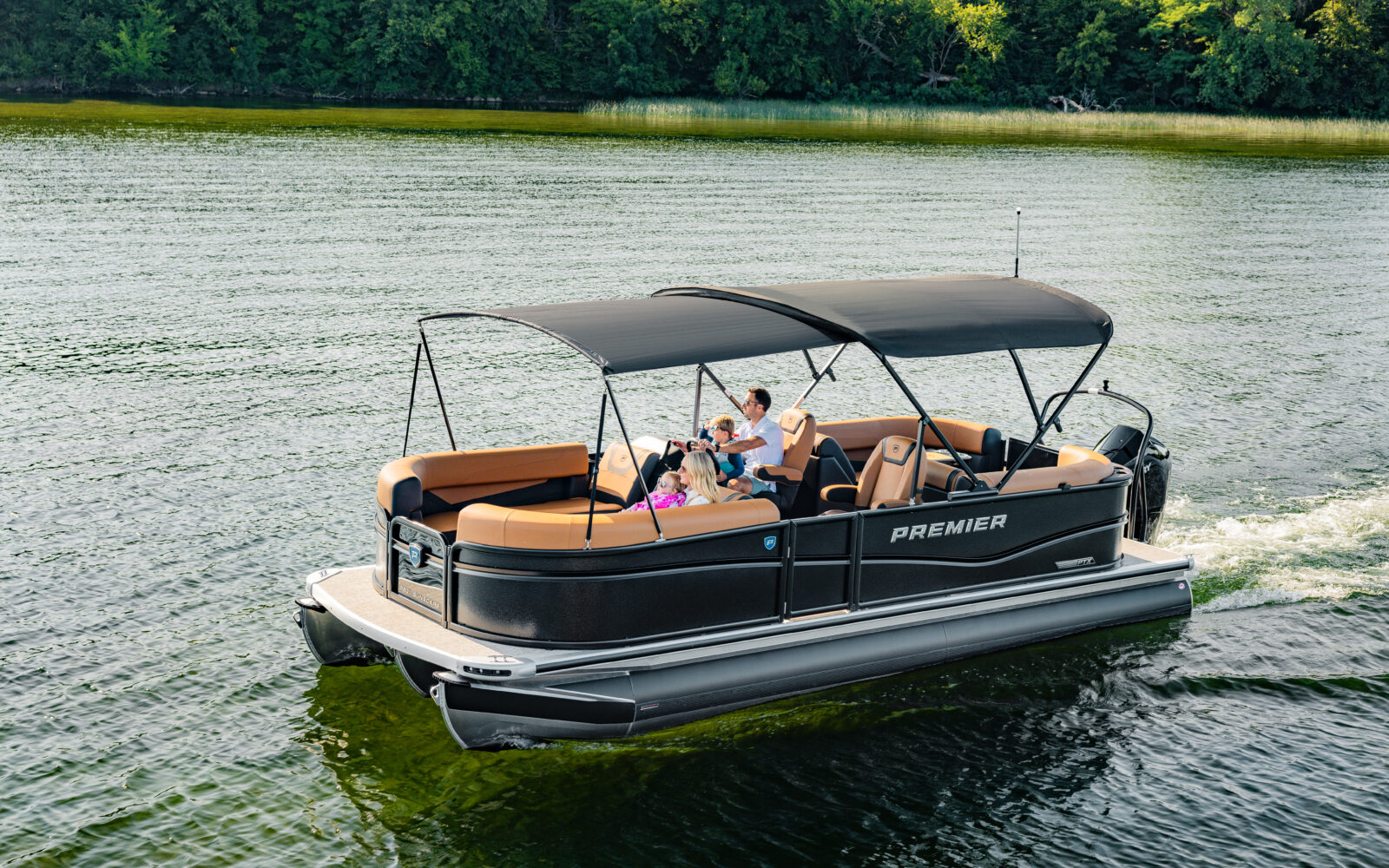 Premier Sunscape pontoon boat with front bimini extension cruising on a lake.