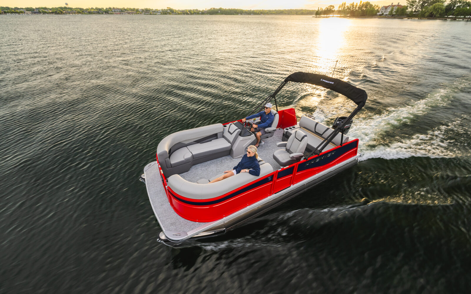 Premier Sunscape pontoon boat cruising at sunrise on a lake.