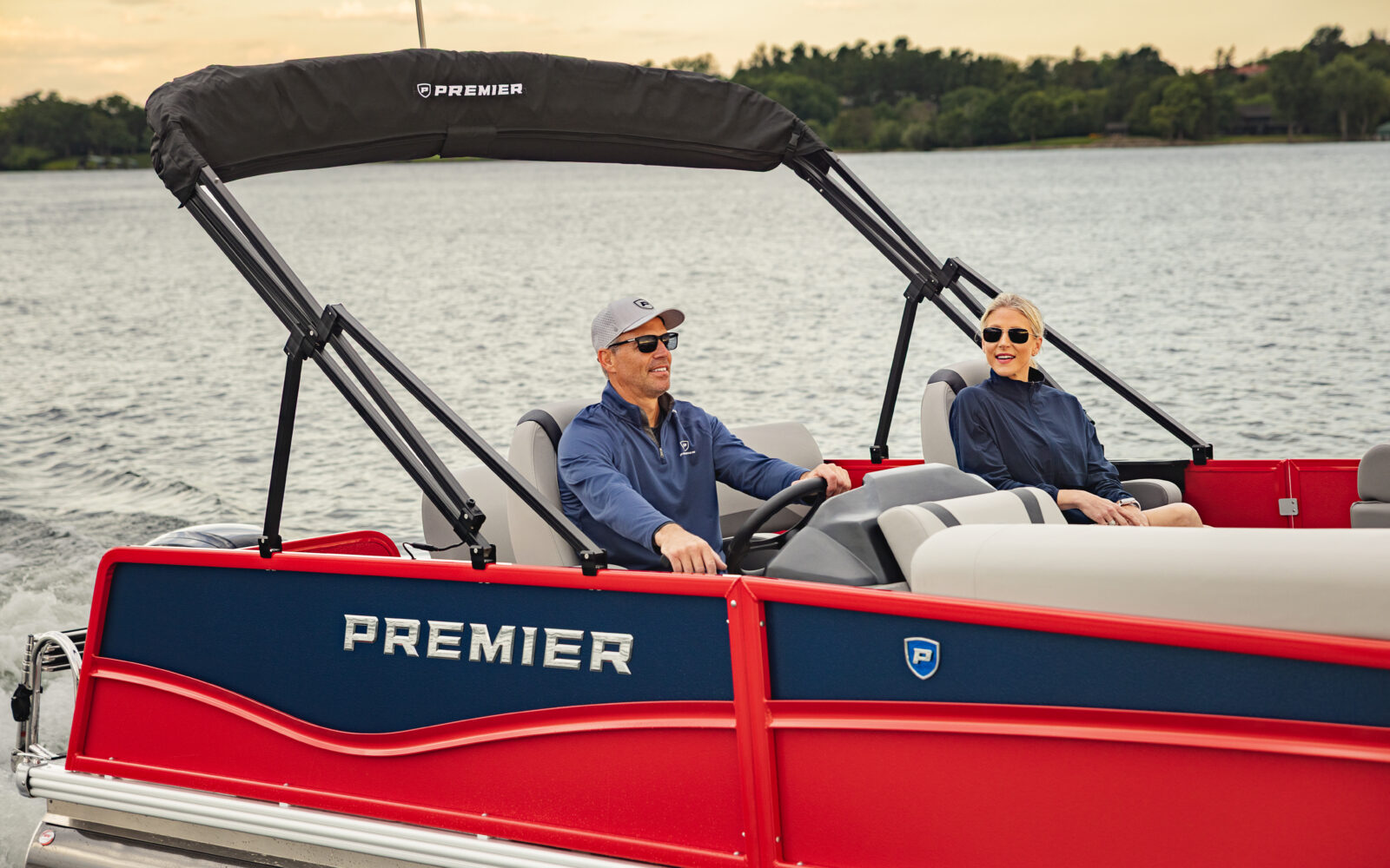 Premier Sunscape pontoon boat cruising across a lake with passengers onboard.