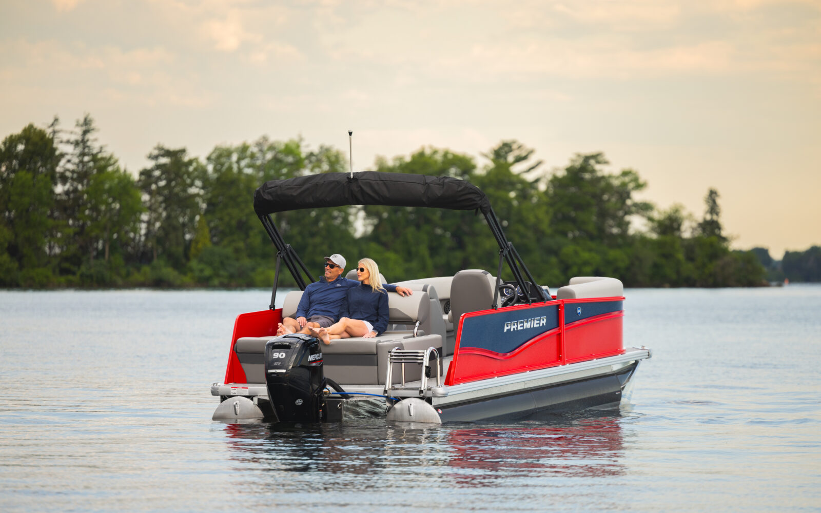 Couple relaxing on the rear lounge of a Premier Sunscape pontoon boat.